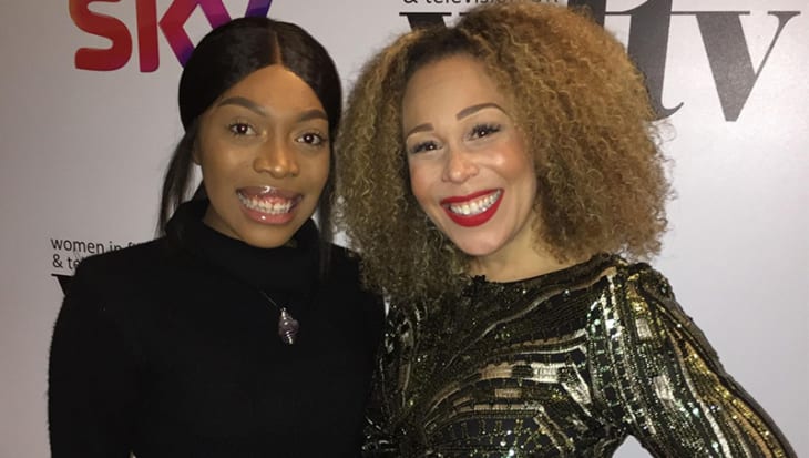 Janay and Ria stand together at award ceremony with a white background with a sky logo