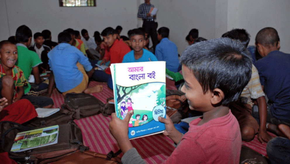 Boy in classroom holding up a book