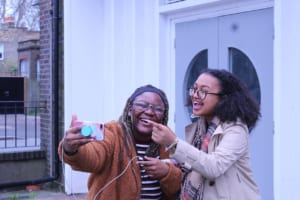 Two girls use their smart phone to film a vlog