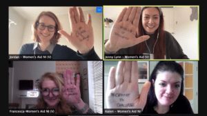 Women's Aid and volunteers at Women's Voice holding their hands up with #ChooseToChallenge written on them