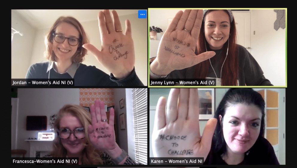 Women's Aid and volunteers at Women's Voice holding their hands up with #ChooseToChallenge written on them