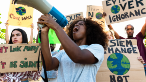 Young people at a climate protest, holding up signs and shouting into a megaphone.