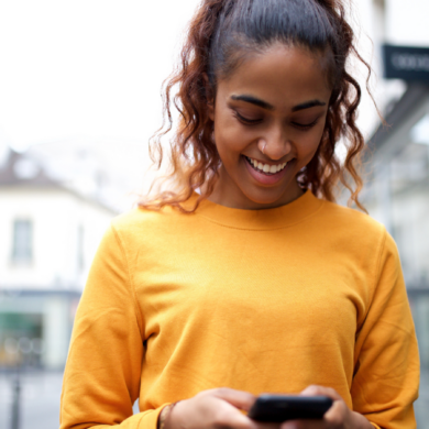A person smiling down at their mobile phone in their hands.