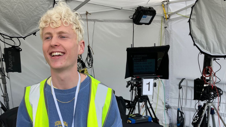Daniel, wearing a Hi Vis jacket, stood under a gazebo and in front of cameras and other production equipment.