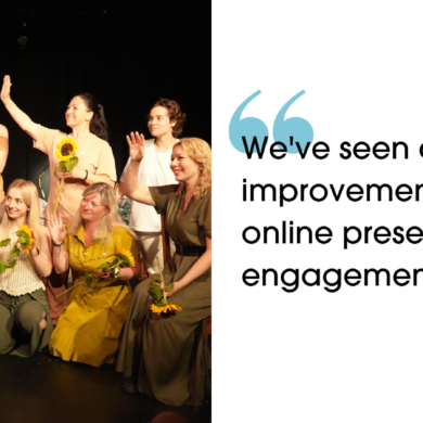 A group of people stood, sat and steeling on a stage. They are waving, smiling and holding sunflowers. 