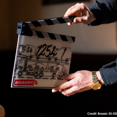 Man's hands holding up television filming clapperboard with scene number and take number for Brassic.