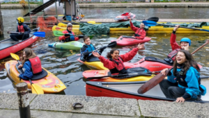 A group of young people in kayaks in the canal.