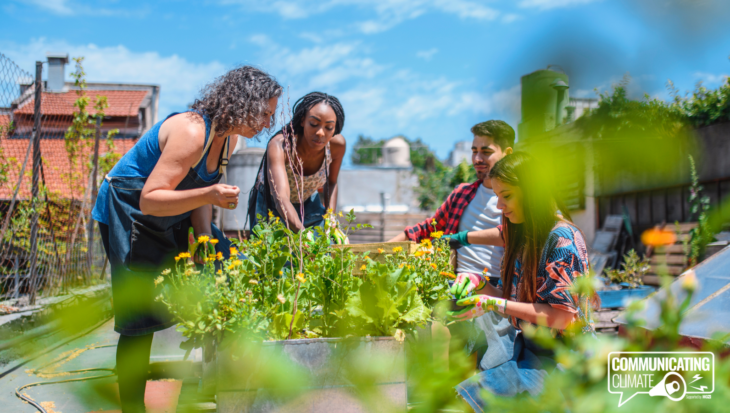 Four people outside, surrounding a large flowerbed. In the logo is the Communicating Climate logo.