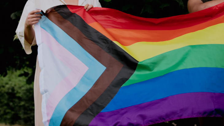 Two people holding the Progress Pride flag.