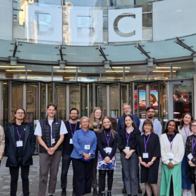 A group of people posing and smiling in front of BBC Broadcasting House.