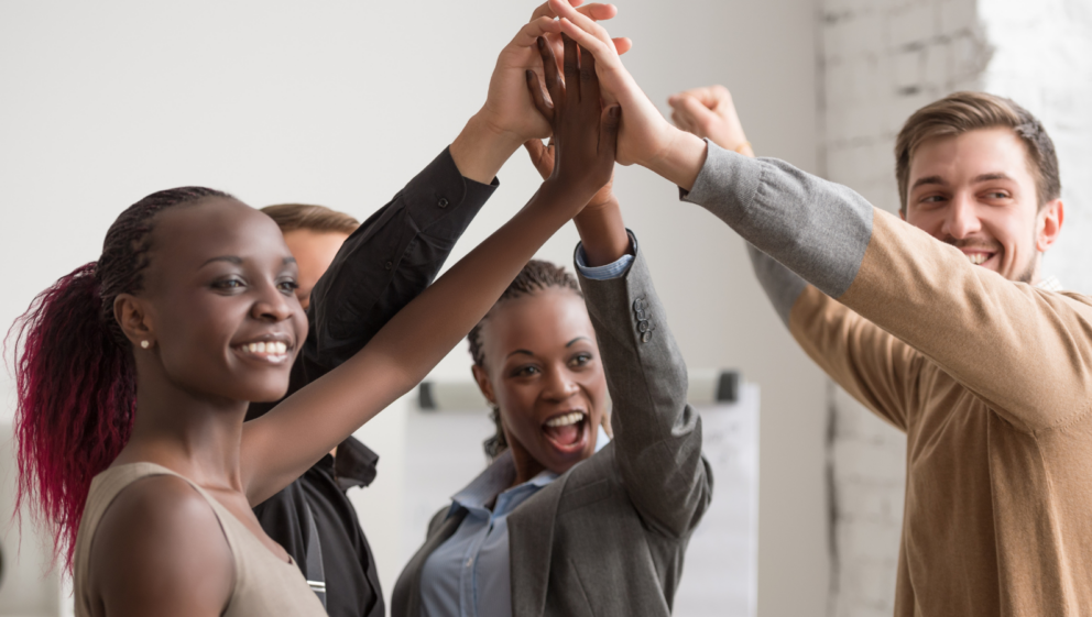 A diverse group of people putting their hands together in the air.