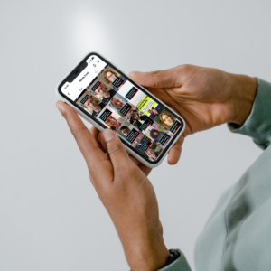 White background with a focus on person's hands holding a smartphone with the Media Trust TikTok account on the screen.