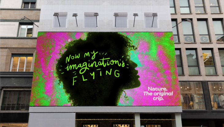 Billboard, on the side of a building of a person's face on a colourful background, with text reading 