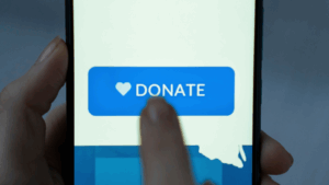 A close-up of a person's finger clicking a 'Donate' button on a mobile phone screen