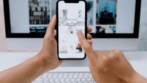 A person holding up their phone to their computer