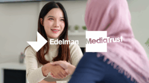 Two people, in an office, shaking hands Edelman and Media Trust logos