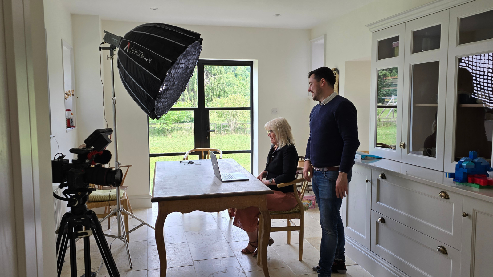 One person sat, at a laptop, with another stood behind them, filming for ADC