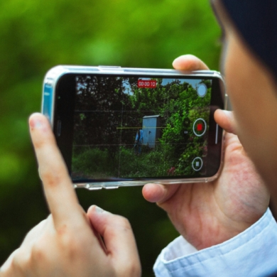 A person, stood outside, filming a video on a mobile phone