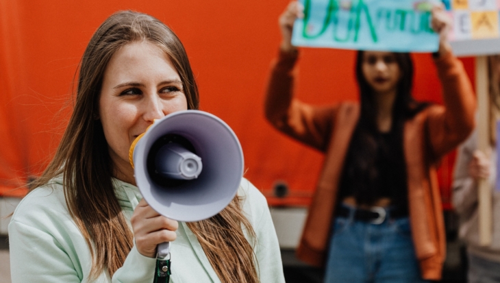 A person speaking into a megaphone, in front of others protesting