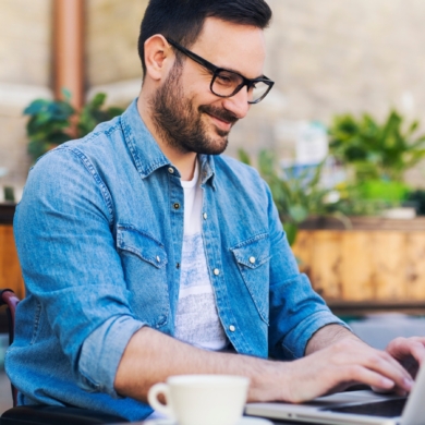 A person smiling as they work on their laptop