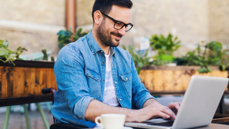A person smiling as they work on their laptop