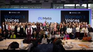 A large group of people stood in front of screens showing logos for Women's Voices, Media Trust Films, Meta and UN Women UK