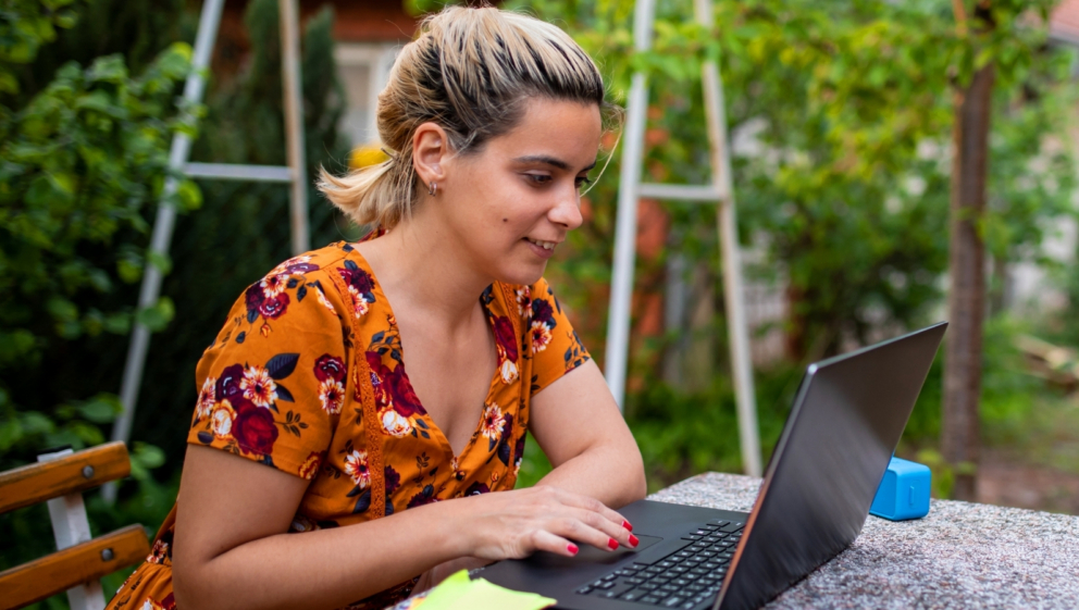 A person sat outside, using a laptop