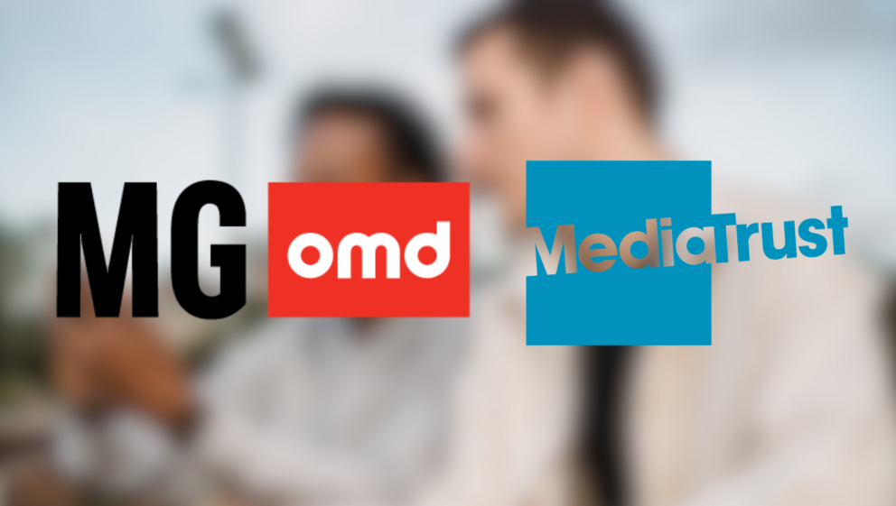 Logos for MG OMD and Media Trust, overlayed on a blurred image showing two people look at a mobile phone