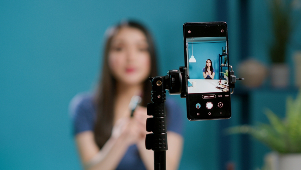 A person filming a video, on a mobile phone on a tripod.