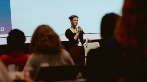 Keli on stage at Women's Voices 2025, holding a mic