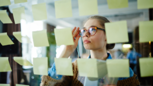 A person looking at a glass screen, covered in sticky notes